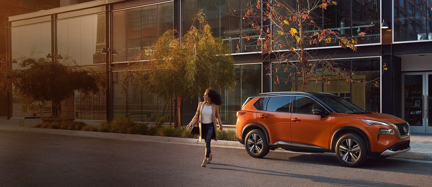 Una mujer con mucha actitud y estilo, cruza la calle mientras vemos una Nissan X-Trail estacionada al fondo