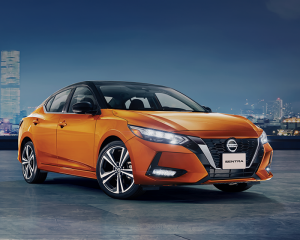 Imagen frontal de Nissan Sentra naranja estacionado cerca de la ciudad