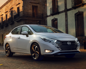 Imagen frontal de Nissan Sentra naranja estacionado cerca de la ciudad