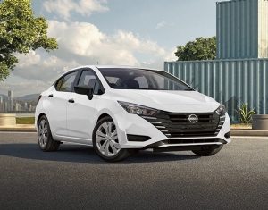 Imagen vista frontal de Nissan V-Drive gris blanco, estacionado rodeado de edificios