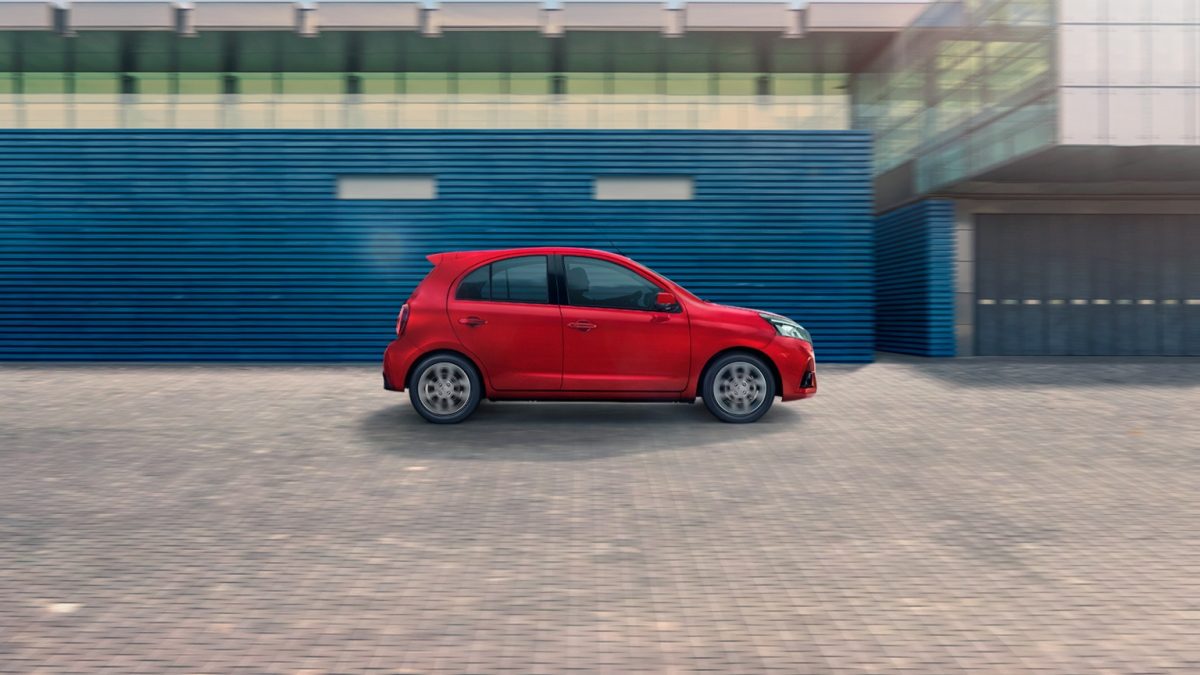 Vista lateral de Nissan March bitono en la calle frente a pared azul