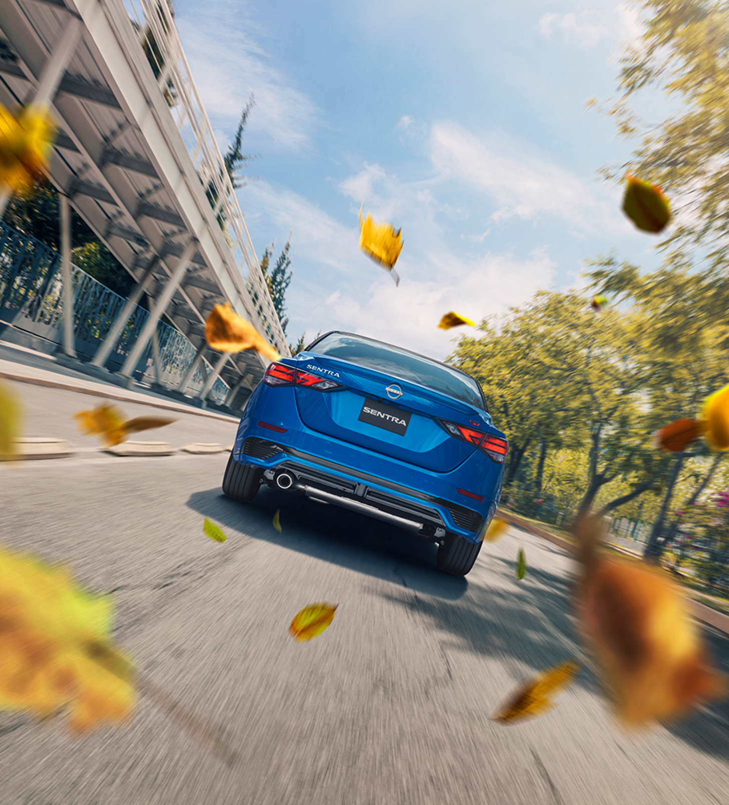 Conduce hacia las oportunidades de financiamiento con esta toma dinámica del Nissan Sentra 2024 rodeado de hojas de otoño danzantes.