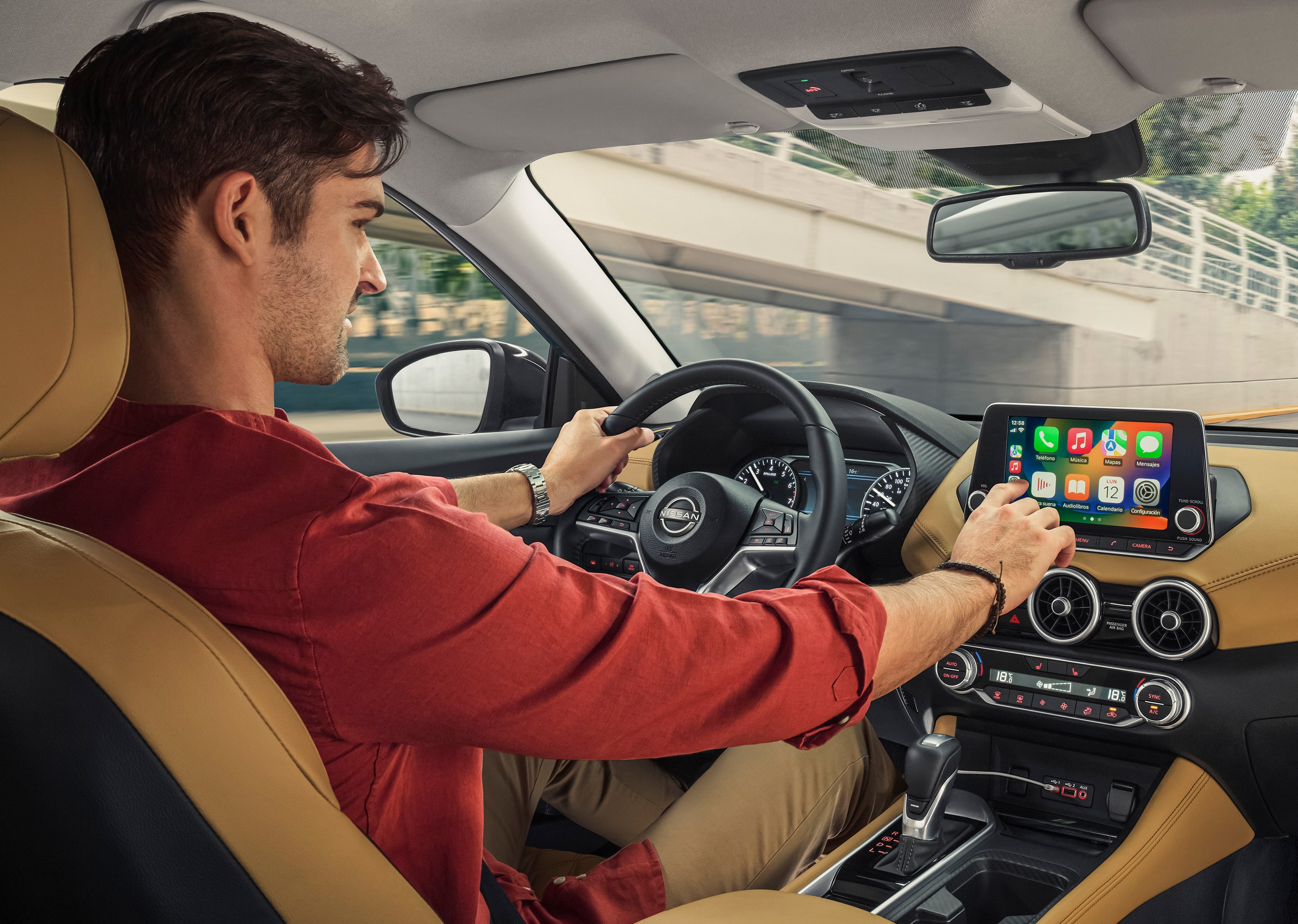 Interior del Nissan Sentra 2024 mostrando la integración de tecnologías de Nissan Intelligent Mobility mientras el conductor interactúa con la pantalla de info entretenimiento resaltando la integración de Apple Carplay y Android Auto
