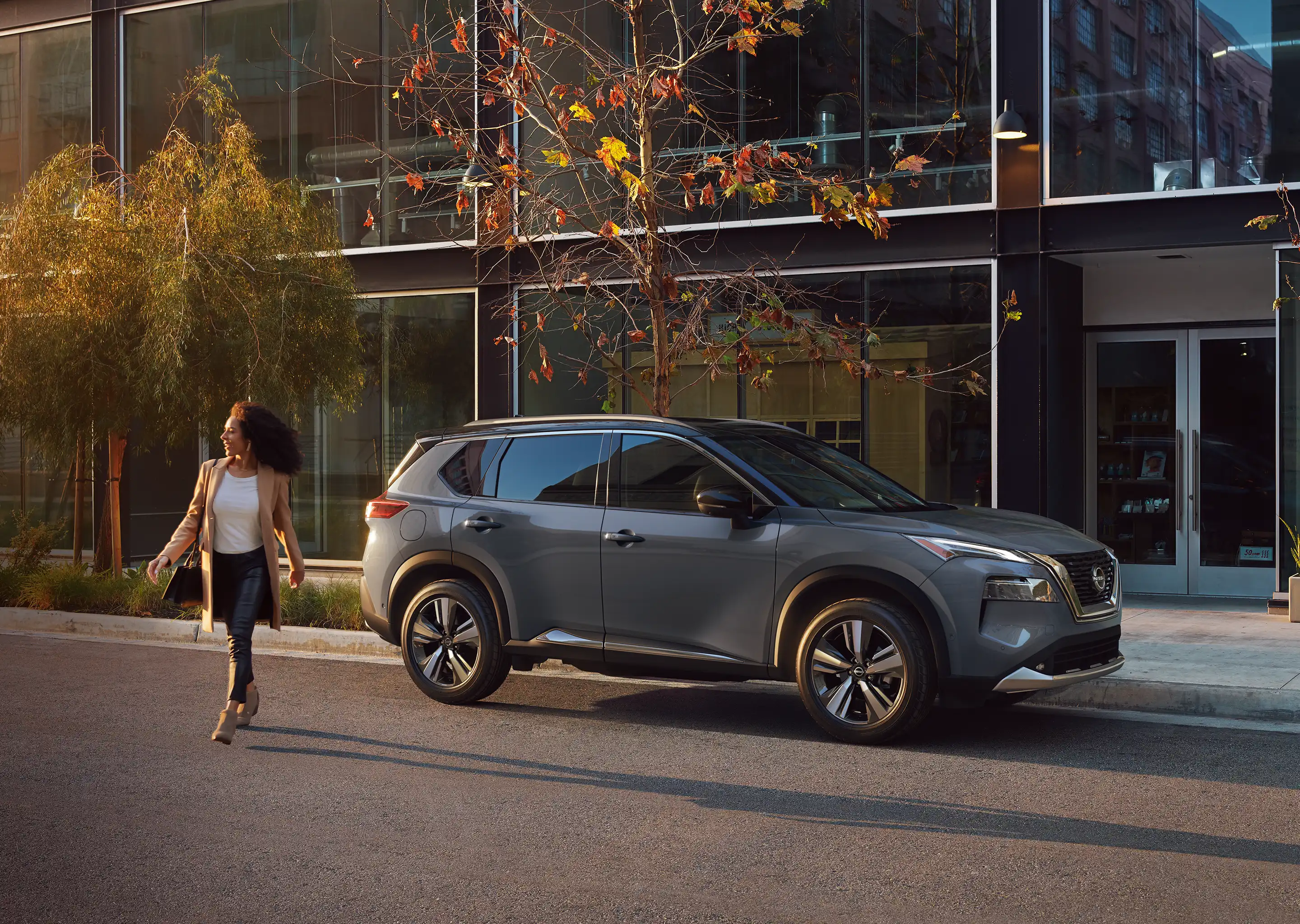 Diseño lateral de la SUV Nissan X-Trail 2025 con mujer caminando.
