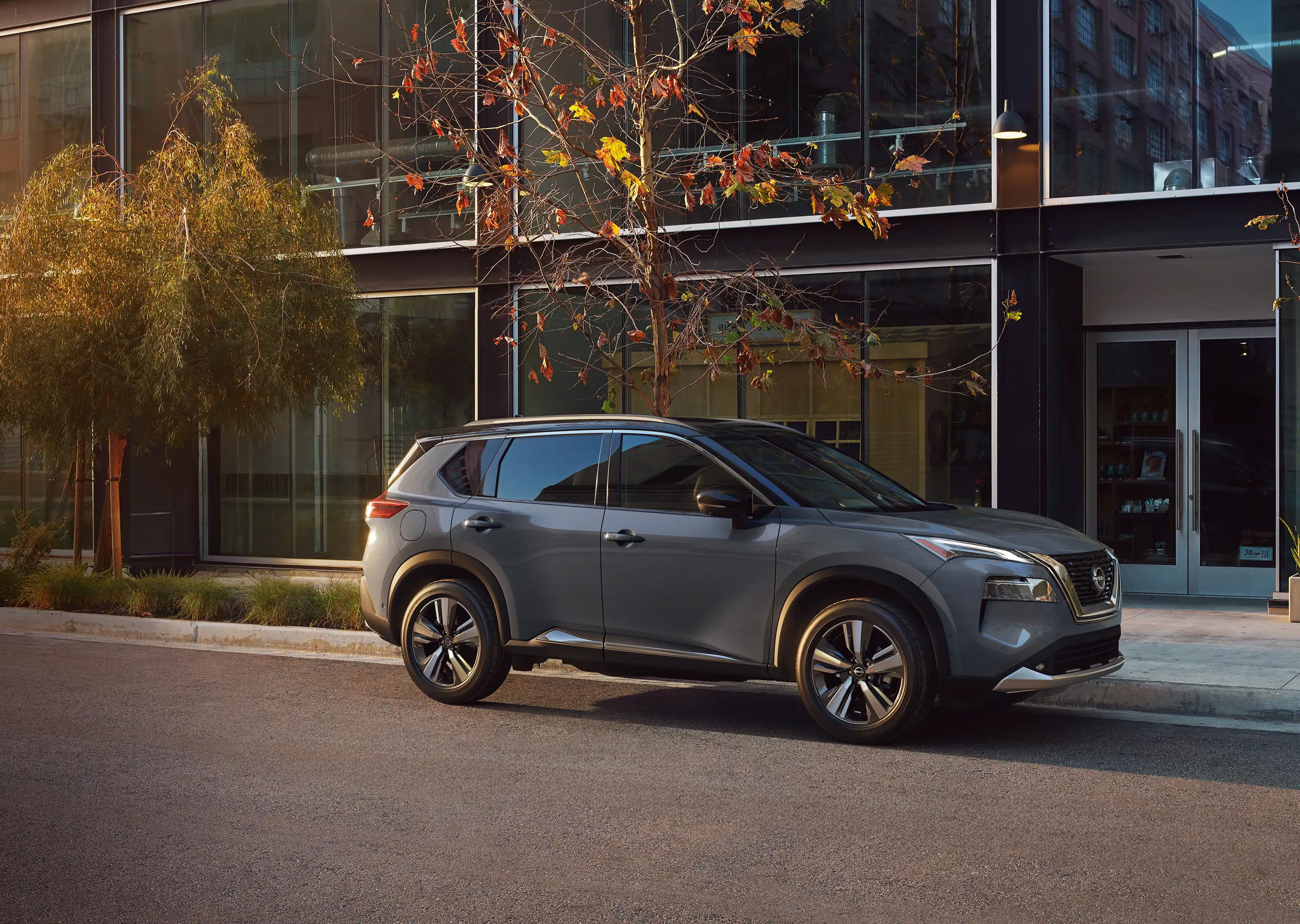 Diseño lateral de la SUV Nissan X-Trail 2026 con mujer caminando.