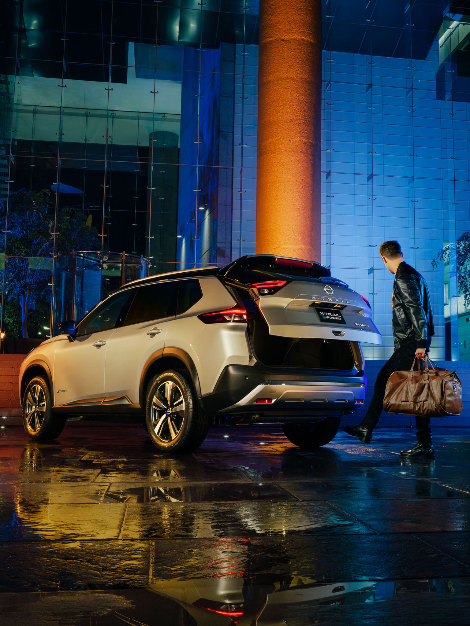 Vista trasera tres cuartos de Nissan X-Trail e-POWER con pareja abriendo cajuela con sistema de apertura no touch.