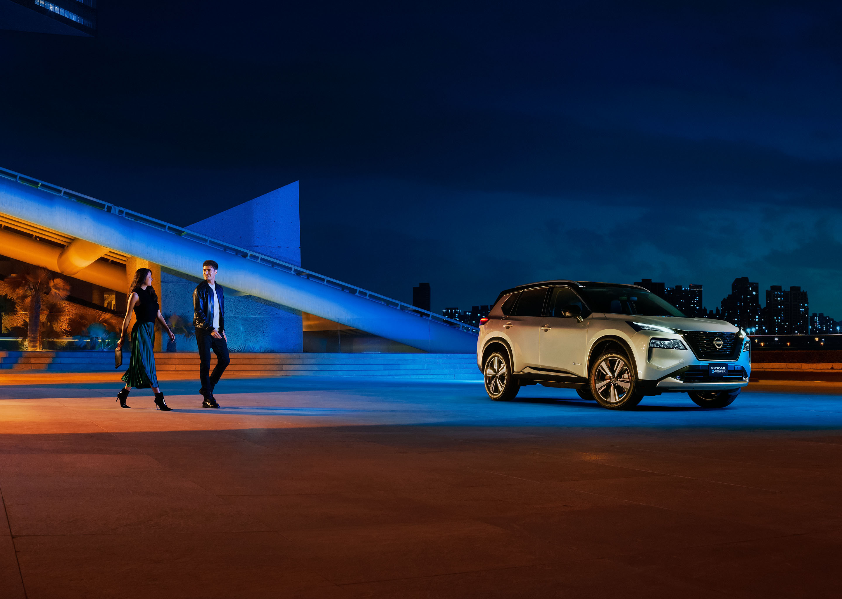 Vista lateral de Nissan X-Trail e- POWER con pareja caminando con el poder para cada hoy.