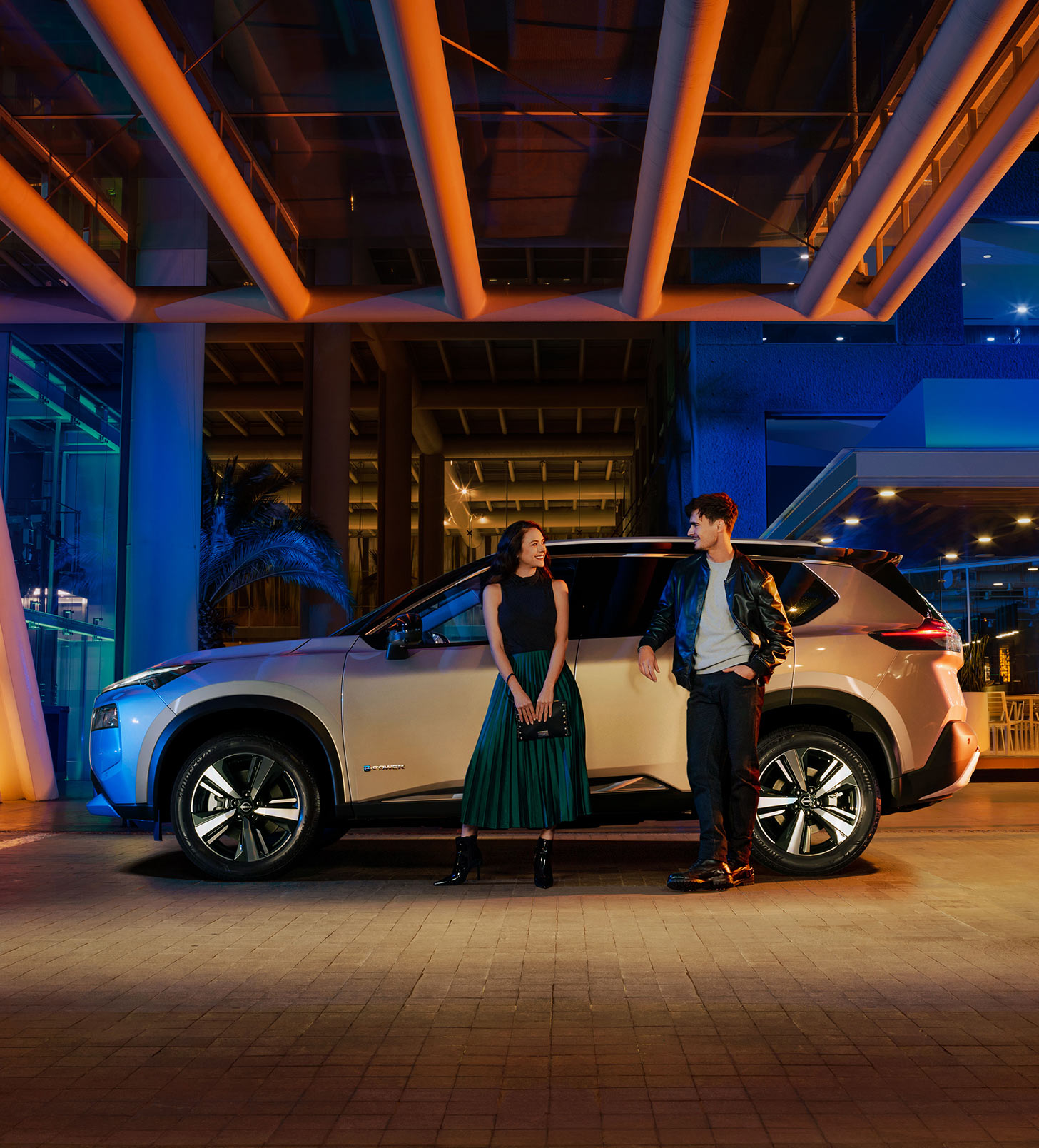 Pareja recargada en SUV X-Trail e-POWER 2025 esperando el Servicio de mantenimiento