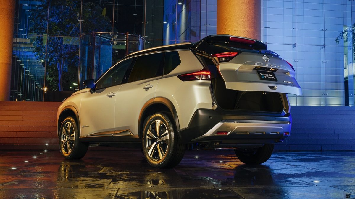 Vista trasera de SUV Nissan X-Trail e-POWER 2026 con pareja abriendo cajuela con sistema de apertura no touch con amplio espacio de almacenamiento.