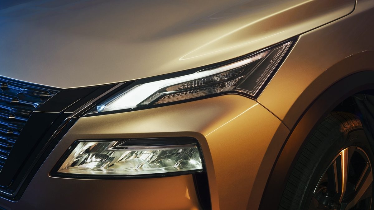 SUV Nissan X-Trail e-POWER 2026 con faros color champagne con hombre al costado con Signature Lamps con todo el poder electrizante.