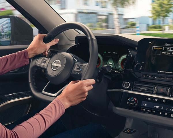 Un par de manos sostienen el volante de un Nissan, podemos ver detalles del interior del vehículo