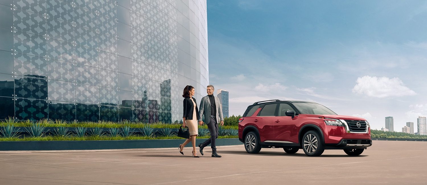 Una pareja de ejecutivos, caminan de la mano en un entorno moderno junto un imponente Nissan Pathfinder