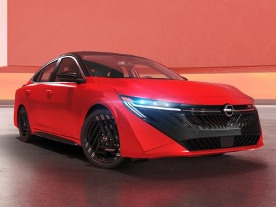 Un hombre camina frente a un Nissan Versa de generación anterior mientras lo mira en un parque citadino