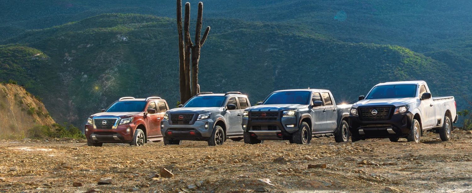 Dos ejecutivos, caminan y sostienen un café mientras se alejan de una Nissan Pathfinder y una Nissan Kicks en un parque urbano